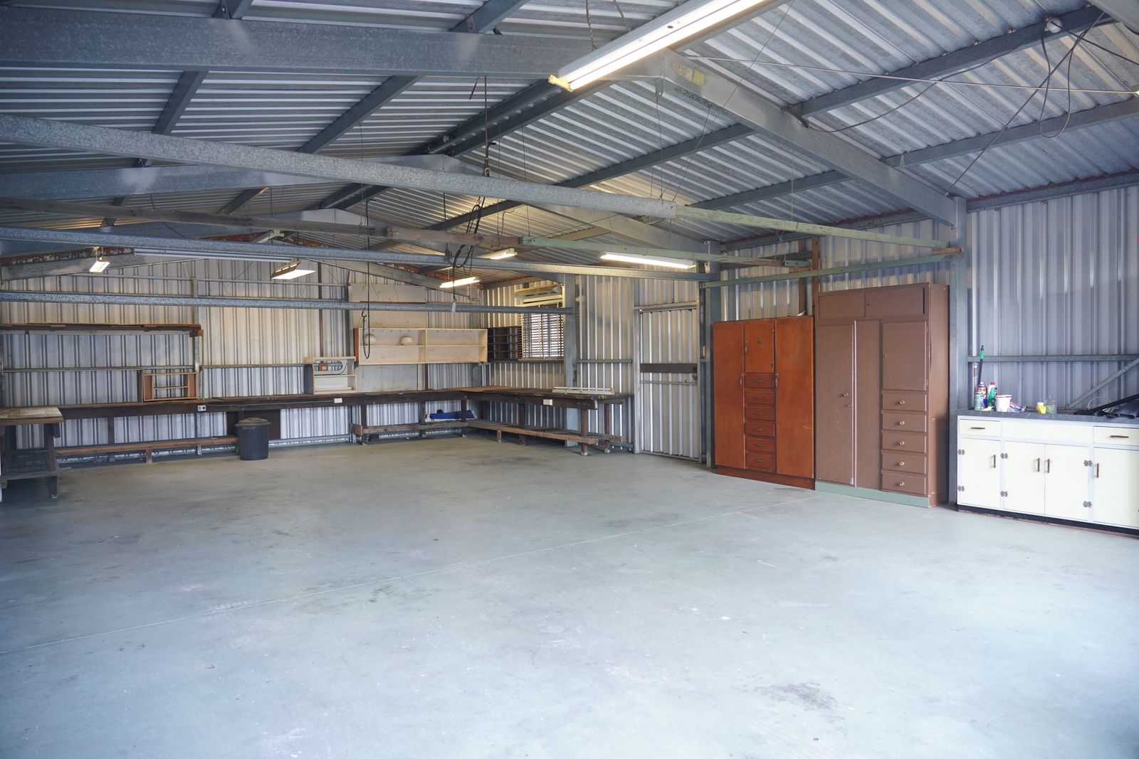 Interior de pavilhão de trabalho com bancadas e paredes em chapa